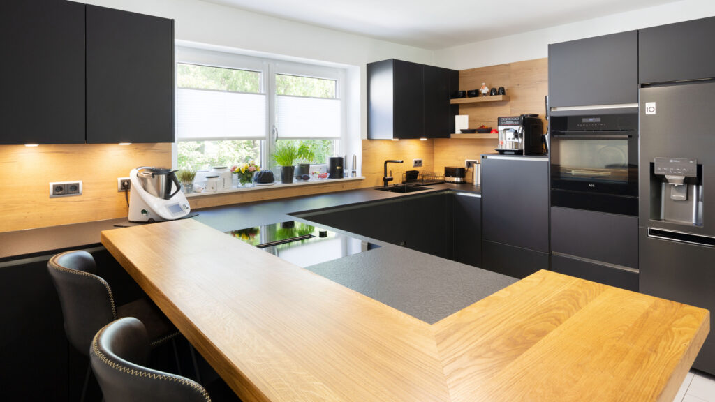 Aschaffenburg Kundenküche matt-schwarz mit Theke und Nischenrückwand in Holz-Optik