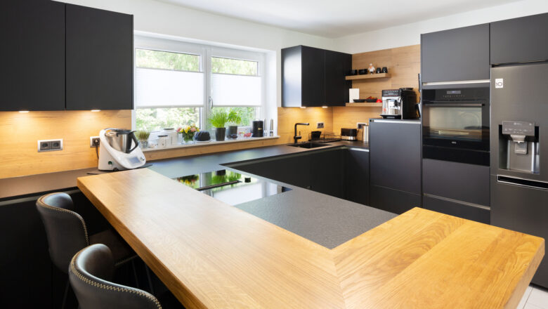 Aschaffenburg Kundenküche matt-schwarz mit Theke und Nischenrückwand in Holz-Optik