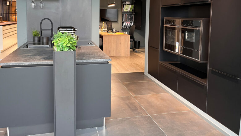 Ausstellungsküche in Inselform mit schwarzen Mattlack-Fronten