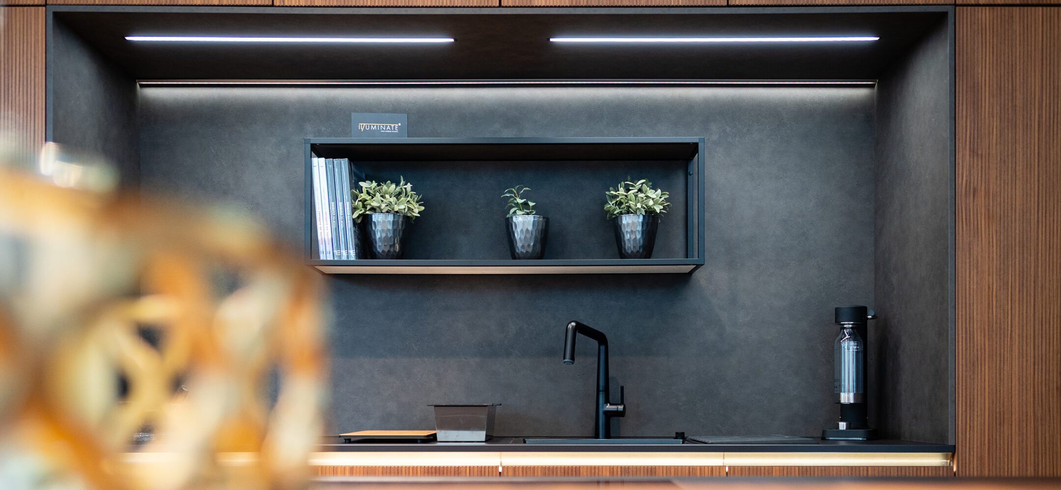 Küchenzeile mit Holzfronten in Rillenoptik, schwarzer Spüle, Metallregal und Nischenrückwand