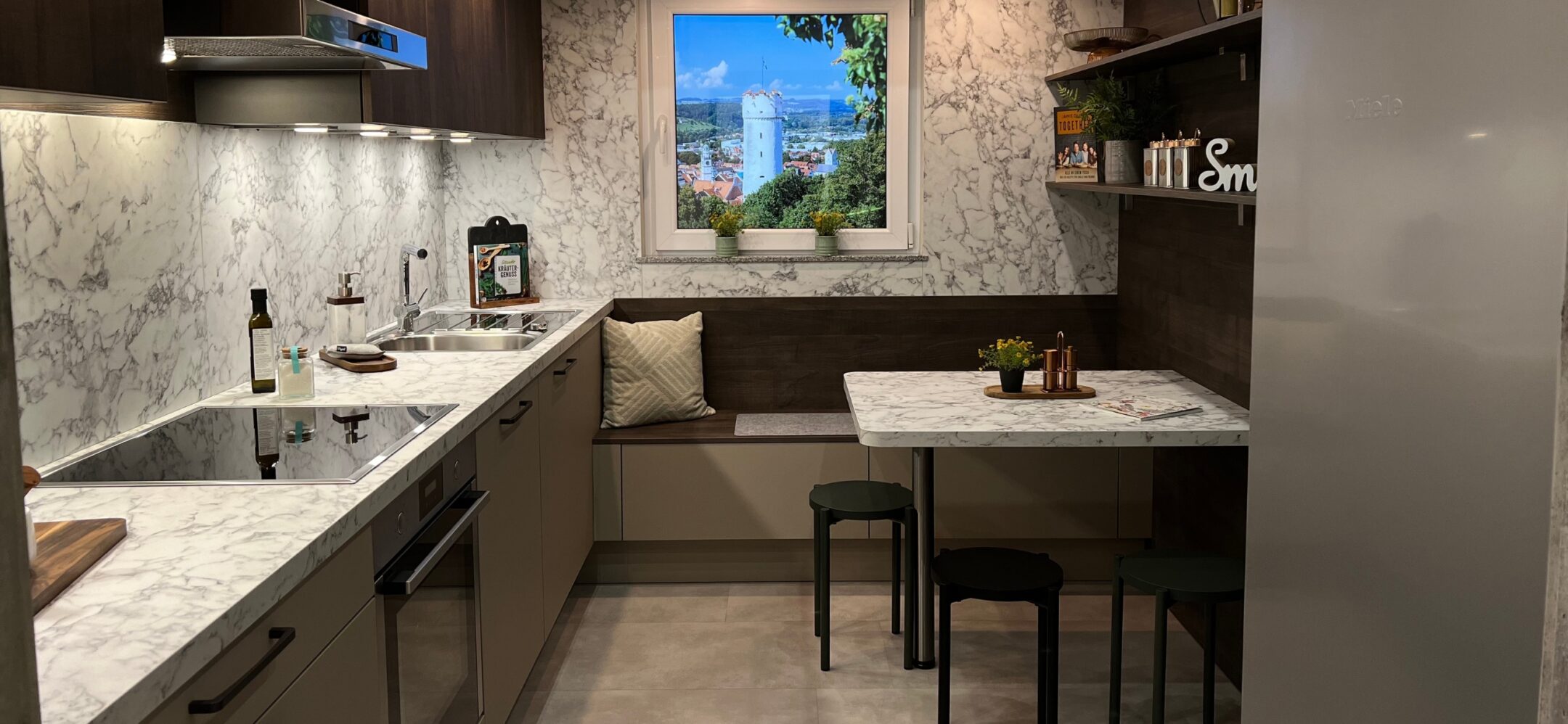 Kleine Küchenzeile mit schwarzen Griffen, Sitzecke und kleinem Esstisch