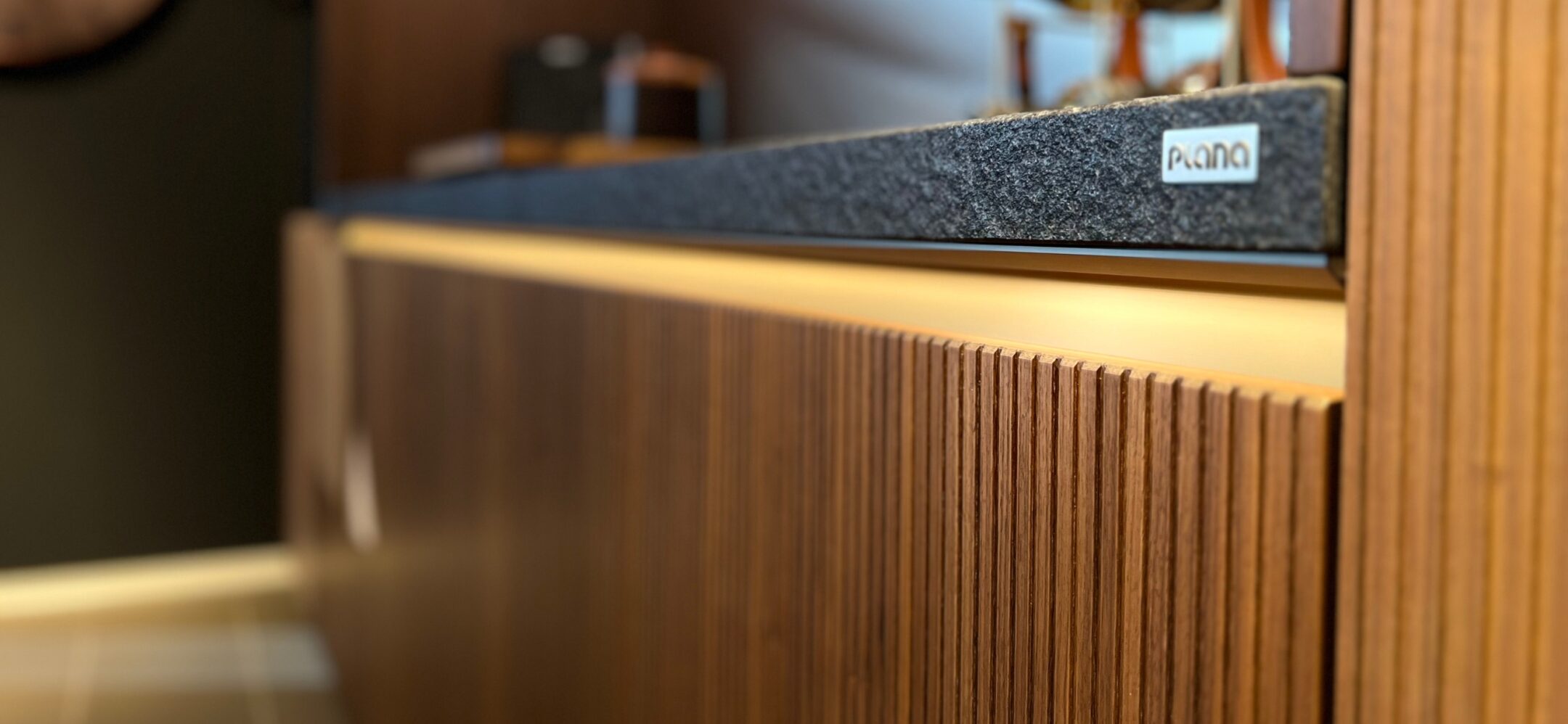 Nahaufnahme Holzfronten in Rillenoptik mit Nahaufnahme Steinarbeitsplatte bei PLANA in Ravensburg