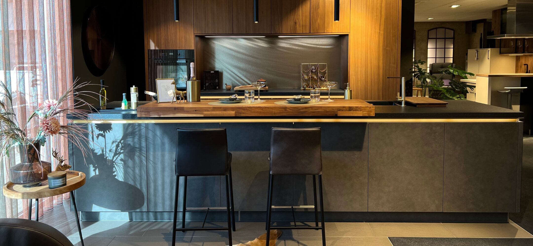 Große Kücheninsel mit Unterbaubeleuchtung und Holztheke mit 2 Barhockern