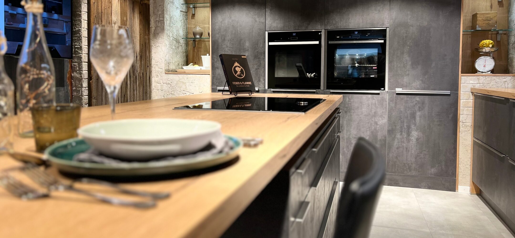 Nahaufnahme Inselküche in Steinoptik mit Holzarbeitsplatte bei PLANA in Ravensburg