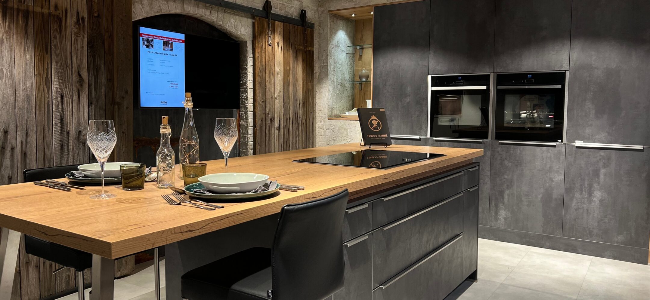 Großzügige Inselküche in Steinoptik mit Holzarbeitsplatte bei PLANA in Ravensburg