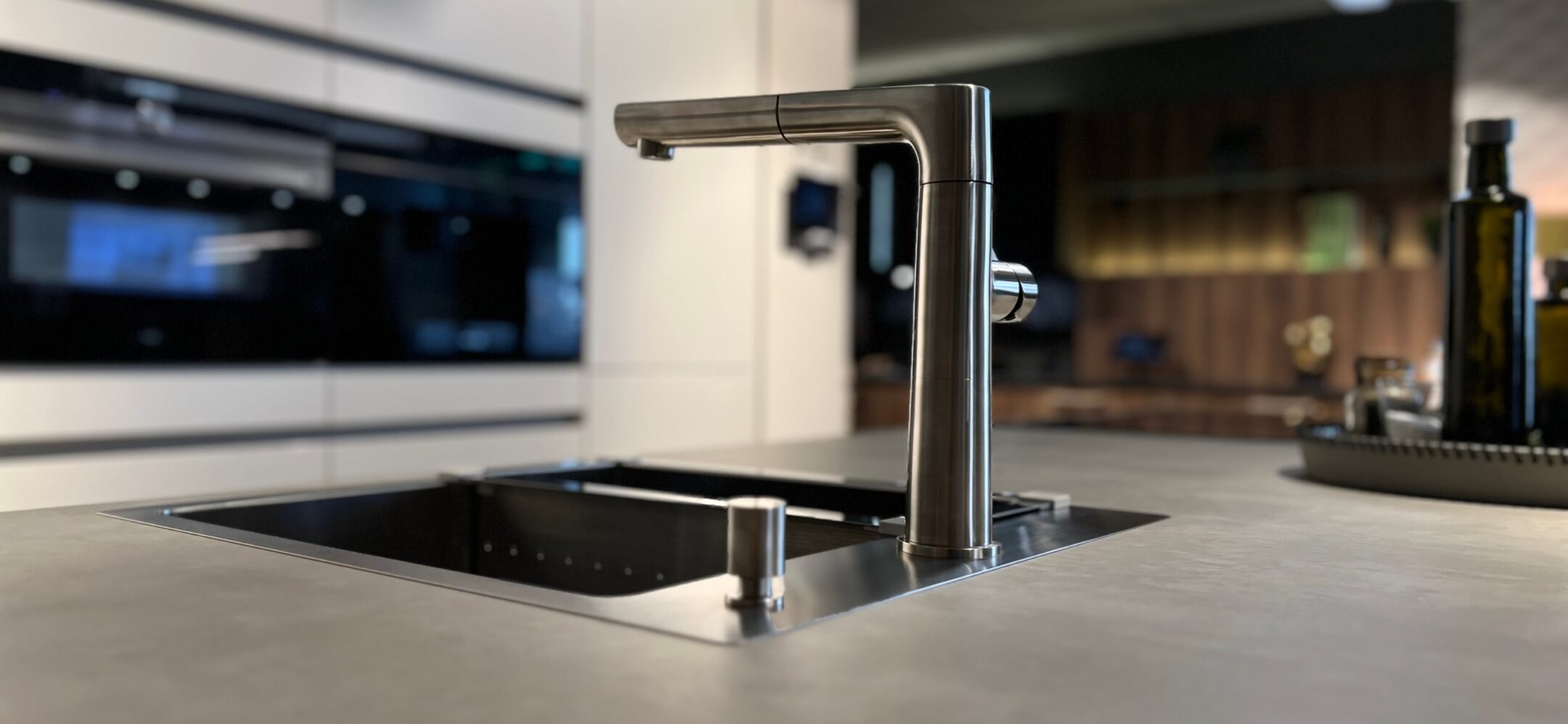 Flächenbündige Spüle mit moderner Mischbatterie auf grauer Keramikarbeitsplatte