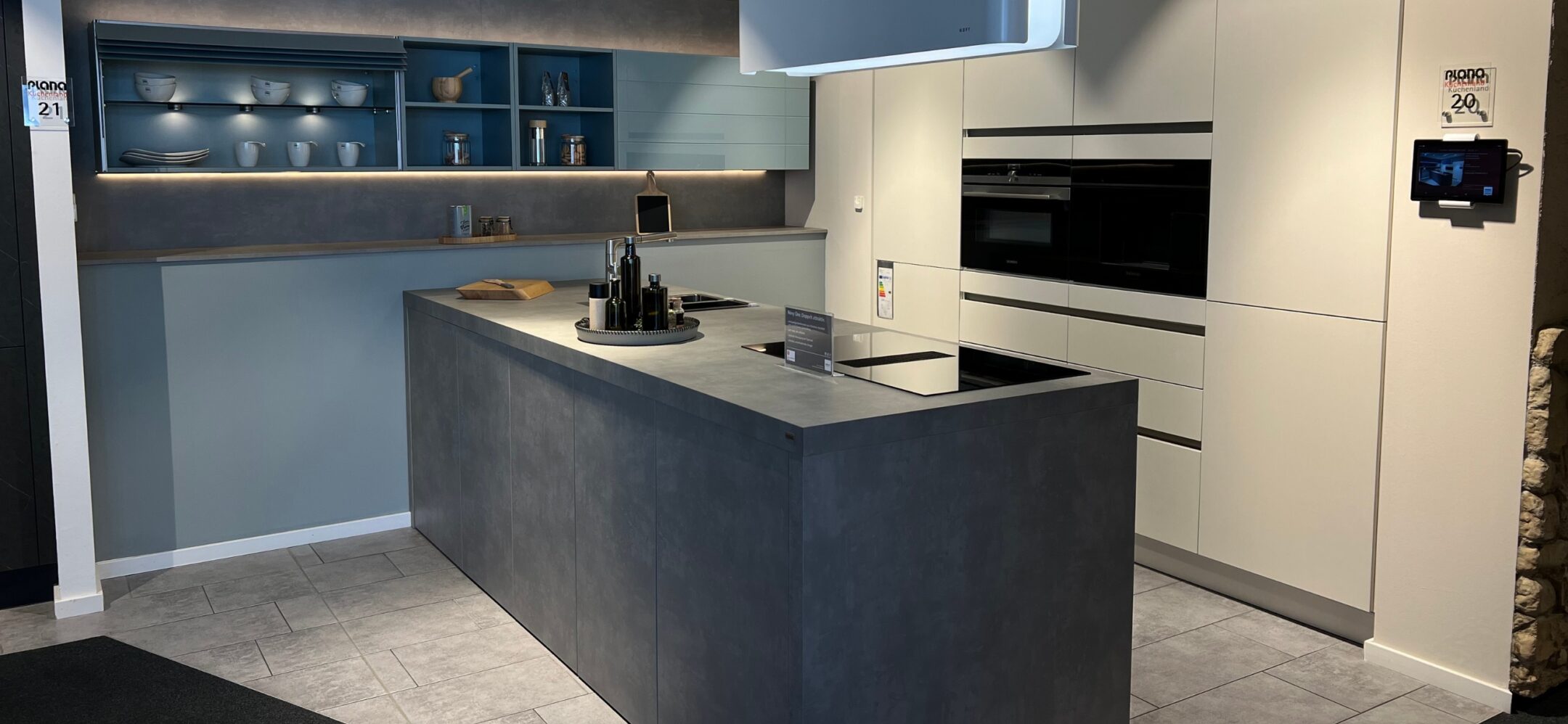 Grifflose Inselküche mit Fronten in Zementgrau und Weiß