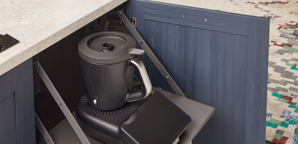 Schrankauszug mit Schwenkarm für eine schwarze Küchenmaschine in einem blauen Unterschrank