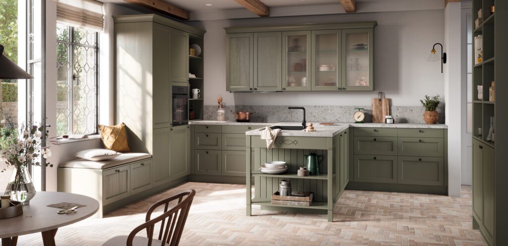Klassische Landhausküche in Salbeigrün mit grauer Steinoptik-Arbeitsplatte und Sitzbank am Fenster.