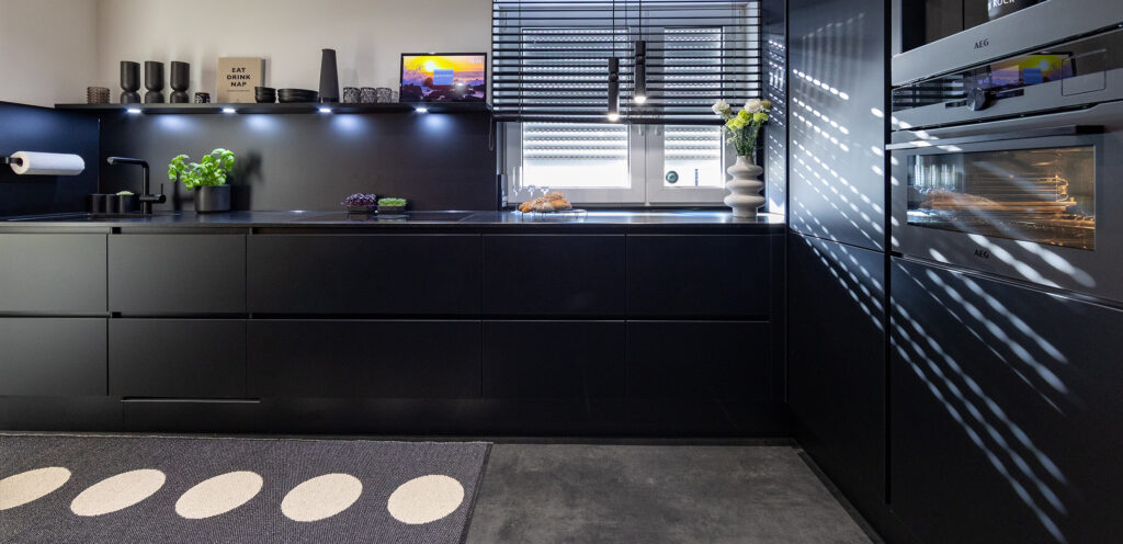 Kundenküche mit schwarzen Fronten und dunkler Steinarbeitsplatte