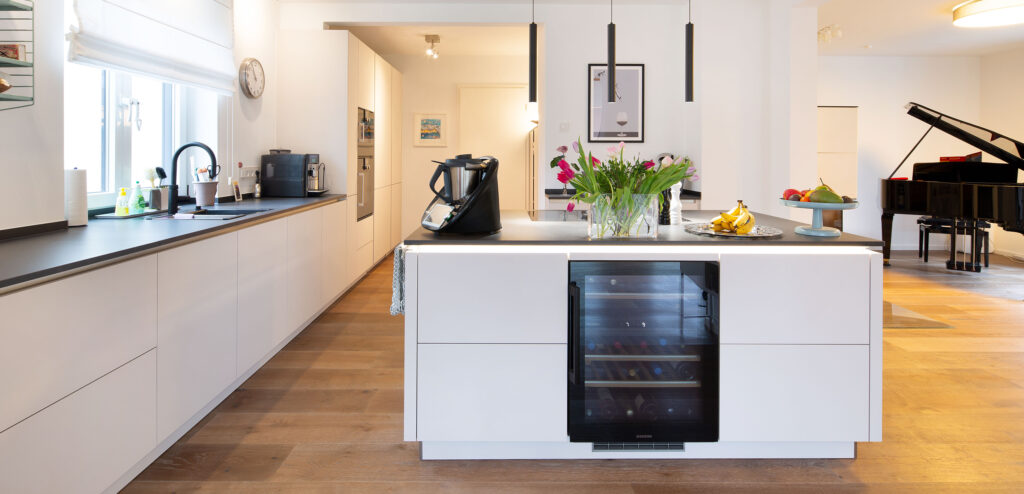 PLANA Küchenausstellung Hilden Insel Kundenküche mit weißen grifflosen Fronten