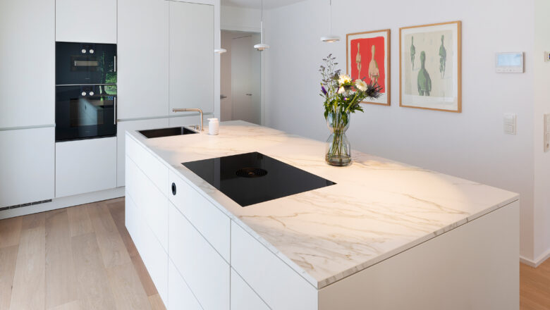 PLANA Küchenstudio Hilden Kundenküche mit weißen Fronten und heller Stein-Arbeitsplatte