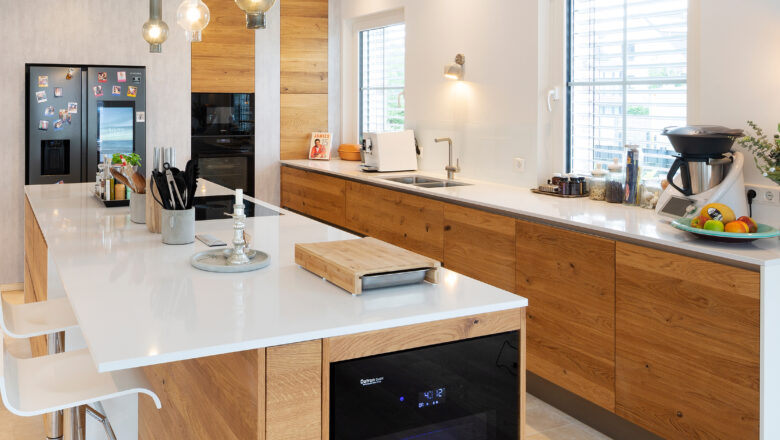 PLANA Küchenstudio Hilden moderne Inselküche mit grifflosen Holzfronten und heller Stein-Arbeitsplatte