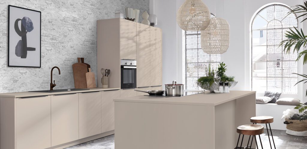 Minimalistische, helle Kücheninsel in Beige vor einer marmorierten Wand.