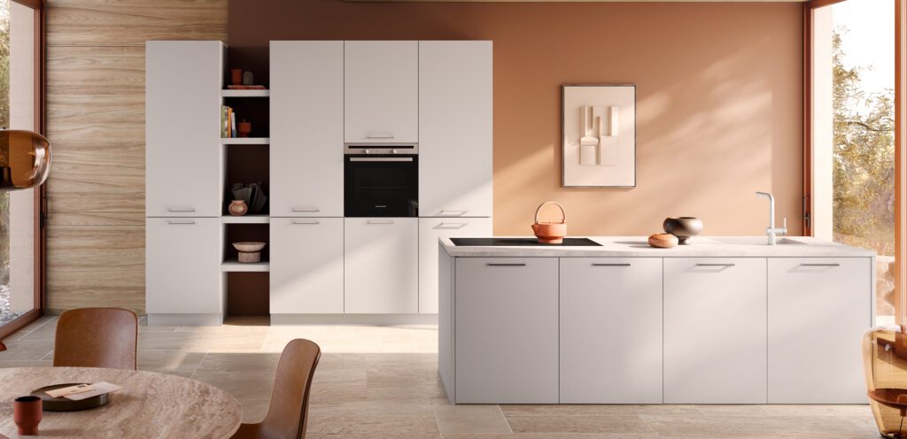 Helle weiße Küche mit Insel vor einer Akzentwand in Terrakotta.