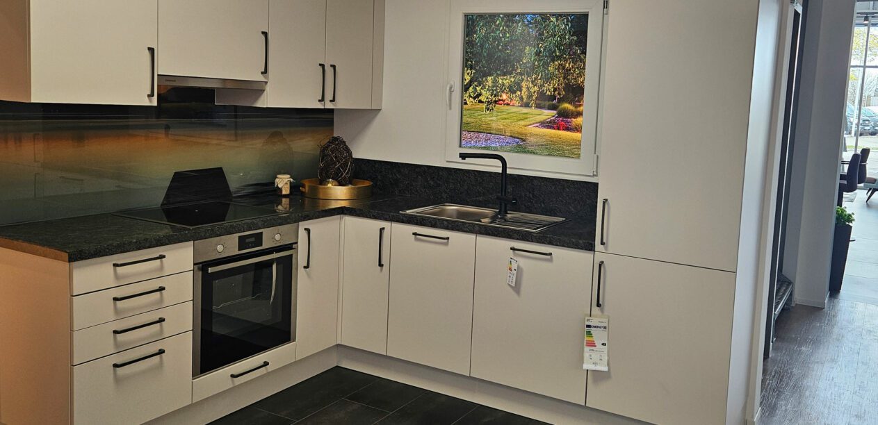 L-Küche mit grauen Mattlack-Fronten und dunkler Naturstein-Arbeitsplatte