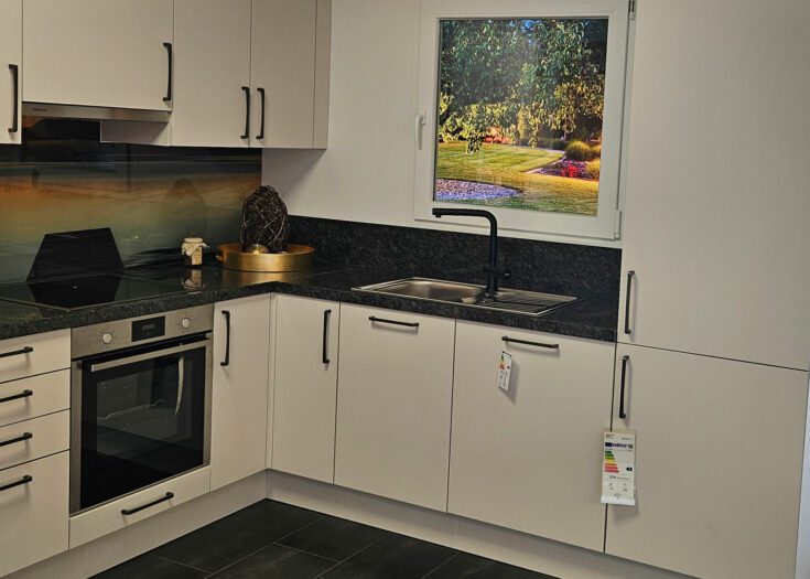 L-Küche mit grauen Mattlack-Fronten und dunkler Naturstein-Arbeitsplatte