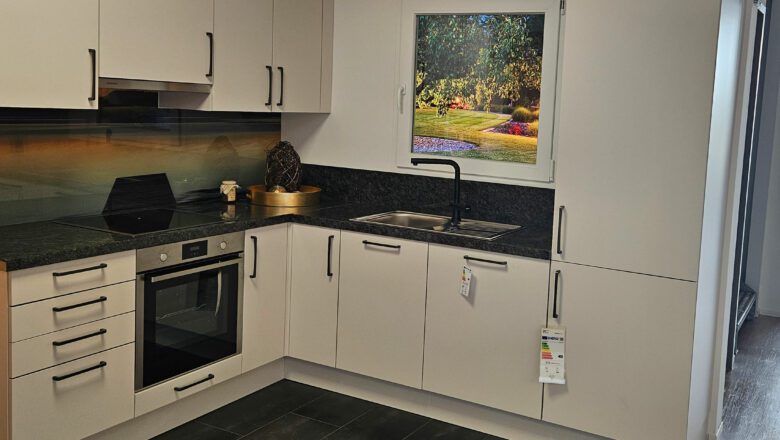 L-Küche mit grauen Mattlack-Fronten und dunkler Naturstein-Arbeitsplatte