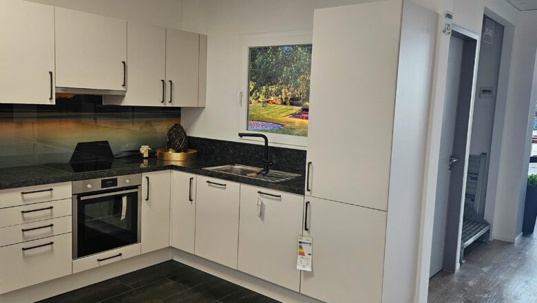 L-Küche mit grauen Mattlack-Fronten und dunkler Naturstein-Arbeitsplatte