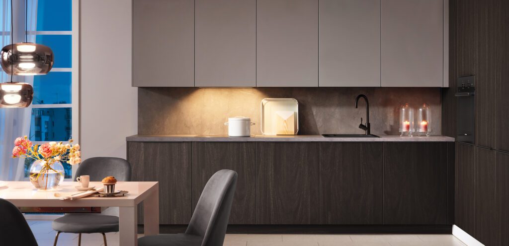 Dunkle L-Küche mit Unterschränken in dunklem Holz und Oberschränken in Grau.