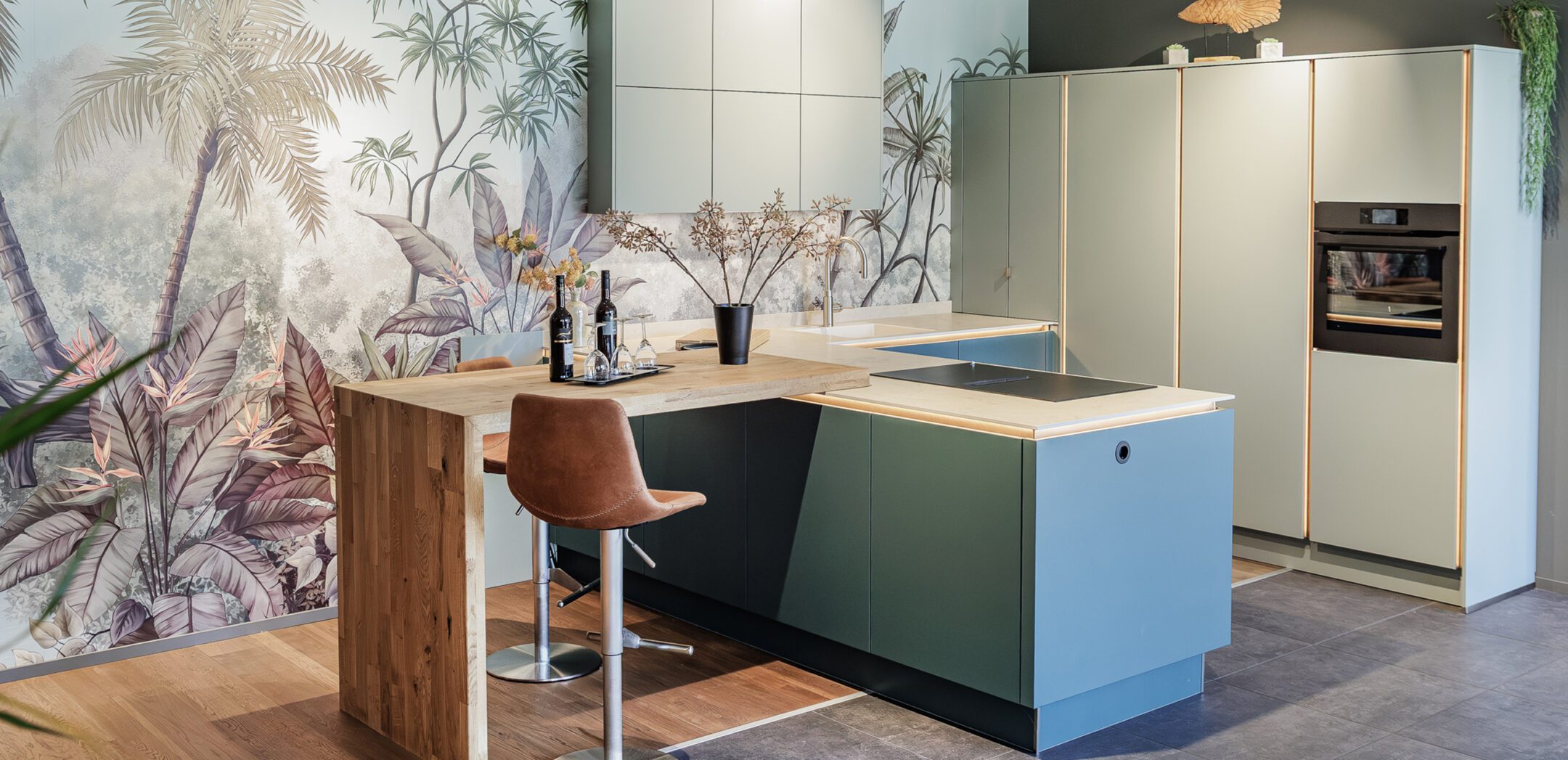 Ansicht einer grünen Design-Küche mit beleuchteten Griffmulden und Barhockern.