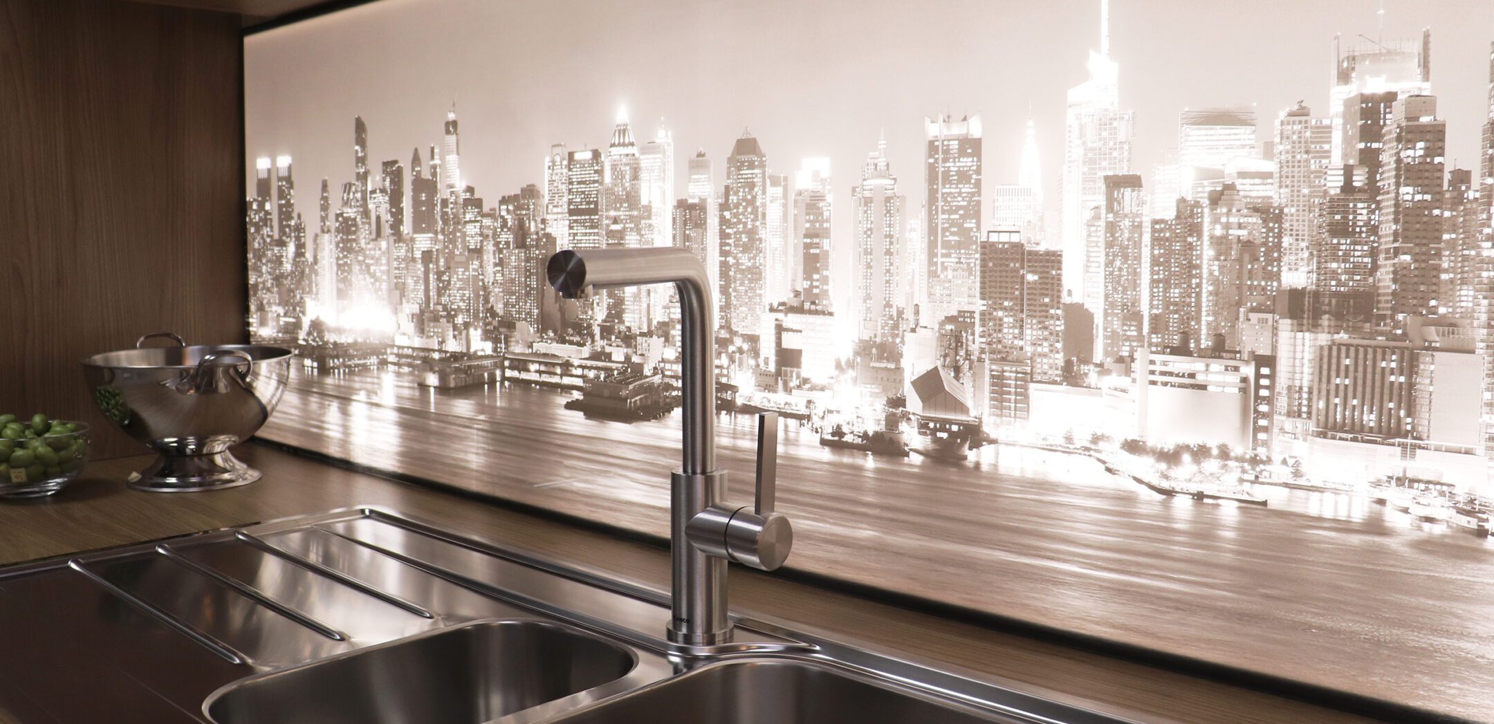 Küchenrückwand mit leuchtendem Skyline-Motiv von New York hinter einer Edelstahl-Armatur.