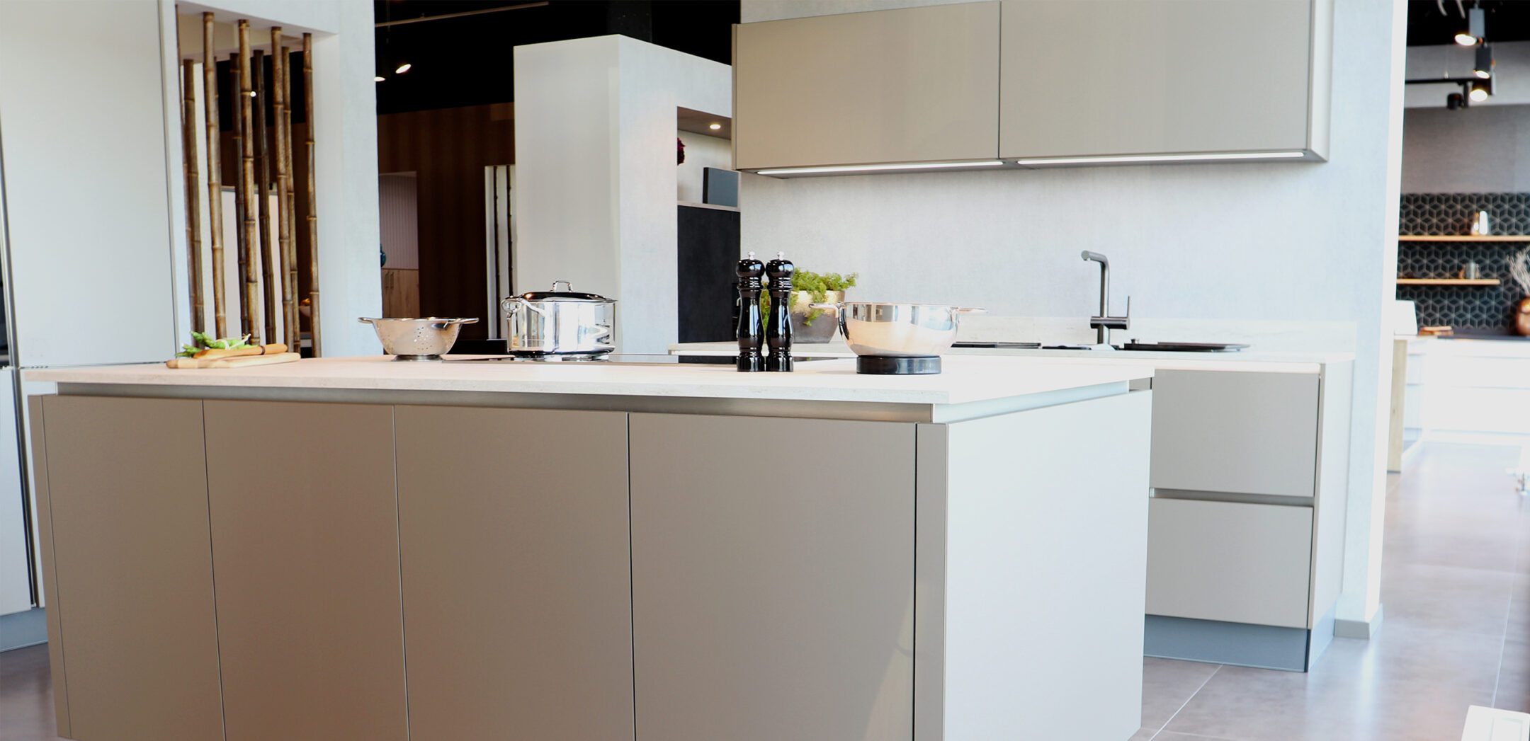 Großzügige Küchenplanung mit Kochinsel und Wandzeile in sanftem Beige-Grau.