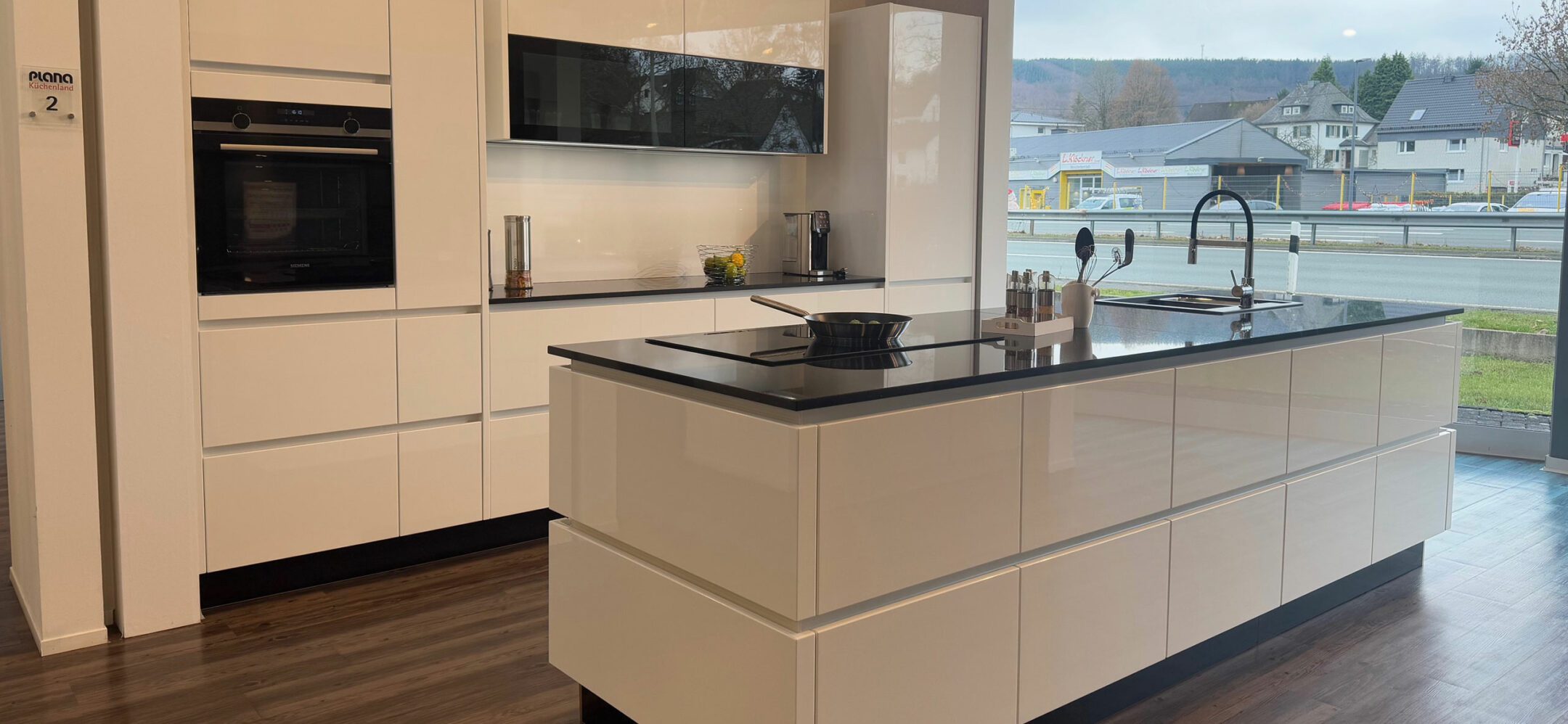 Weiße Inselküche mit hochwertigen Glanzlack-Fronten