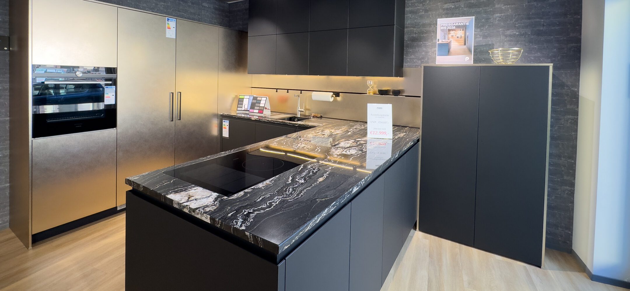 Großzügige U-Küche mit Granit-Arbeitsplatte und Fronten in schwarz und Gold bei PLANA in Sinzheim