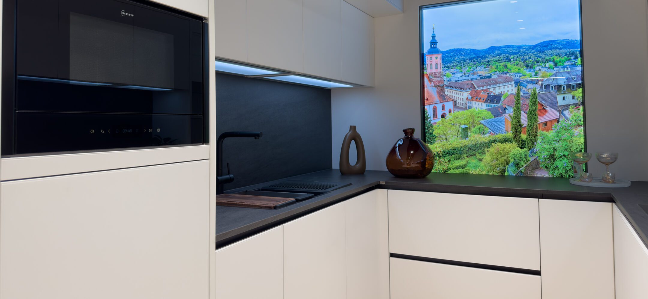 Weiße grifflose Küche mit schwarzem flächenbündigem Spülbecken und Einbaumikrowelle in Sinzheim