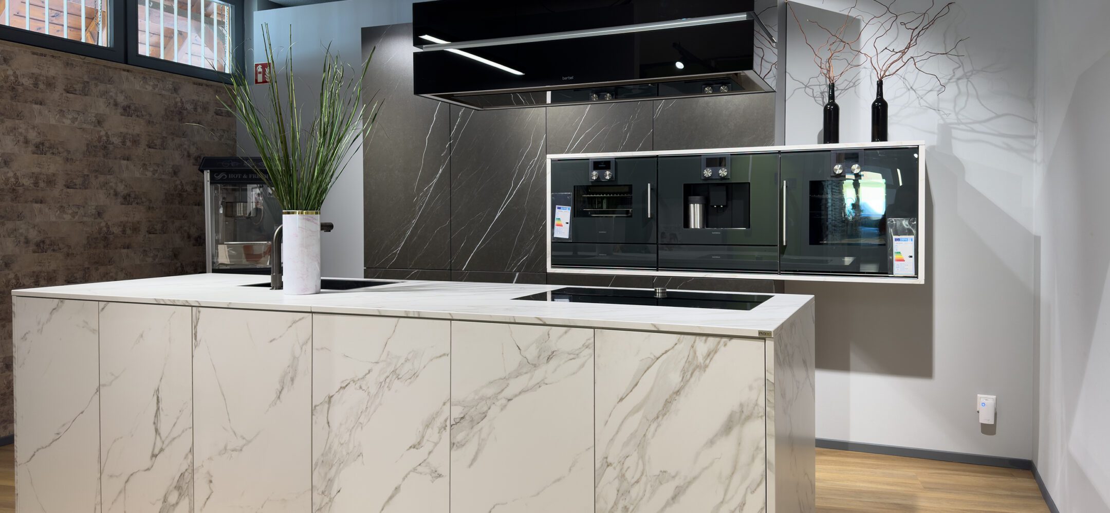 Moderne grifflose Inselküche mit hochwertigen Einbaugeräten bei PLANA in Sinzheim