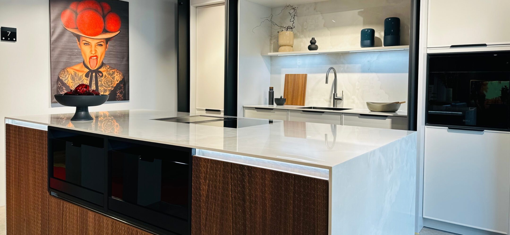 Großzügige Kücheninsel mit Marmor-Dekor, integriertem Kochfeldabzug und modernem Wandbild.