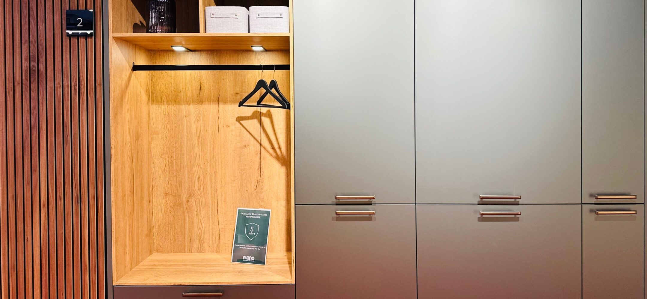 Maßgeschneiderter Garderobenschrank in Eiche-Echtholzoptik kombiniert mit matten, grauen Fronten.