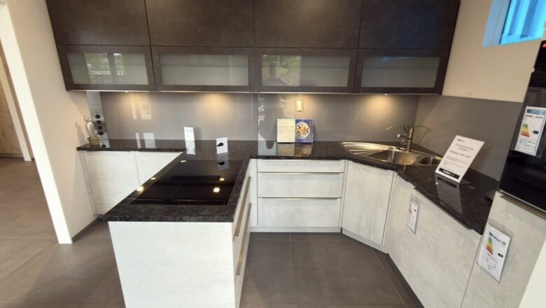 T-Küche mit Arbeitsplatte aus dunklem Naturstein und weißen Fronten