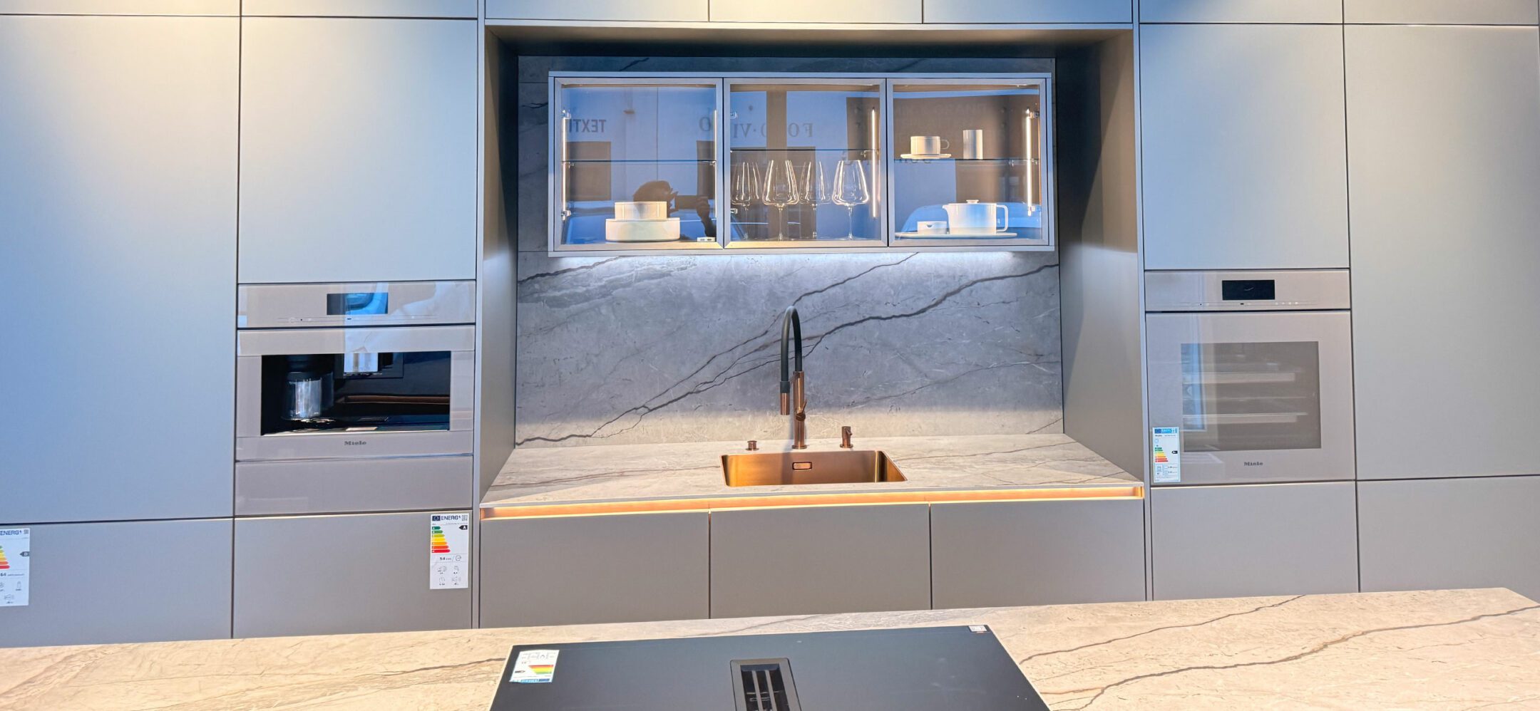 Inselküche mit hellgrauen grifflosen Fronten und hochwertigen Elektrogeräten