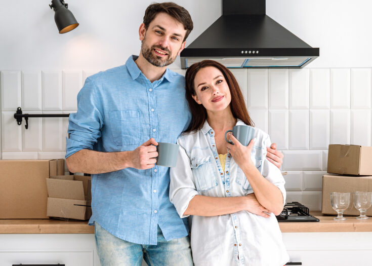 Junges Paar steht mit Kaffeebecher in Küche
