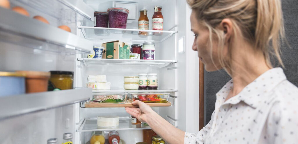 Eine Frau nimmt eine Aufschnittplatte aus dem Kühlschrank