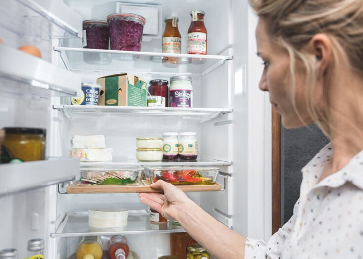 Eine Frau nimmt eine Aufschnittplatte aus dem Kühlschrank