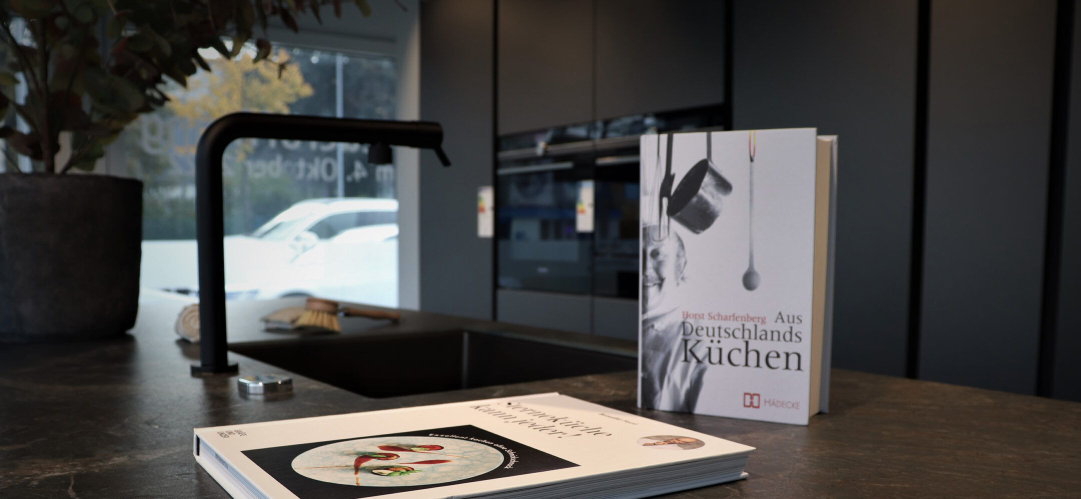 PLANA Küchenstudio Ludwigsburg Dunkle Inselküche mit hochwertiger Küchenarbeitsplatte