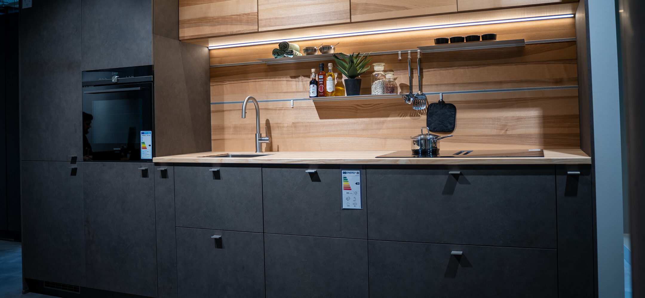 Kleine Küchenzeile mit dunklen Fronten und Holzarbeitsplatte und Holznischenrückwand