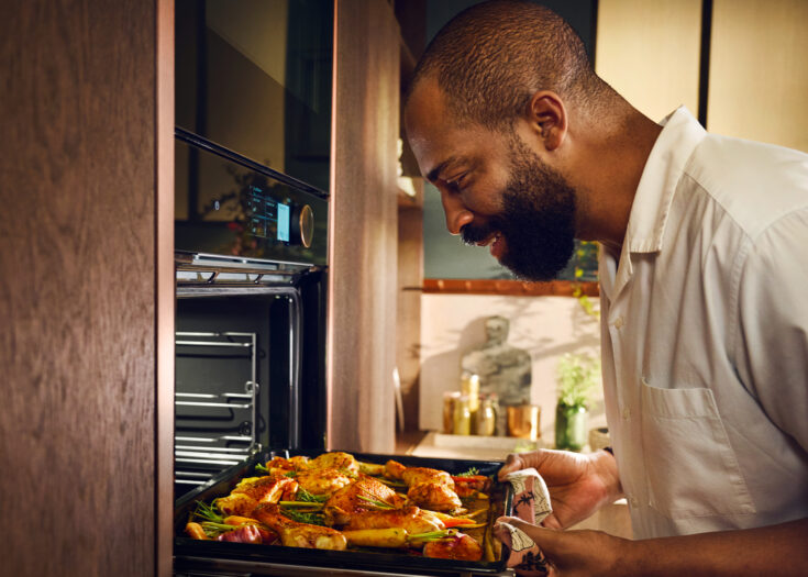 Mann nimmt Backblech aus Neff Einbaubackofen