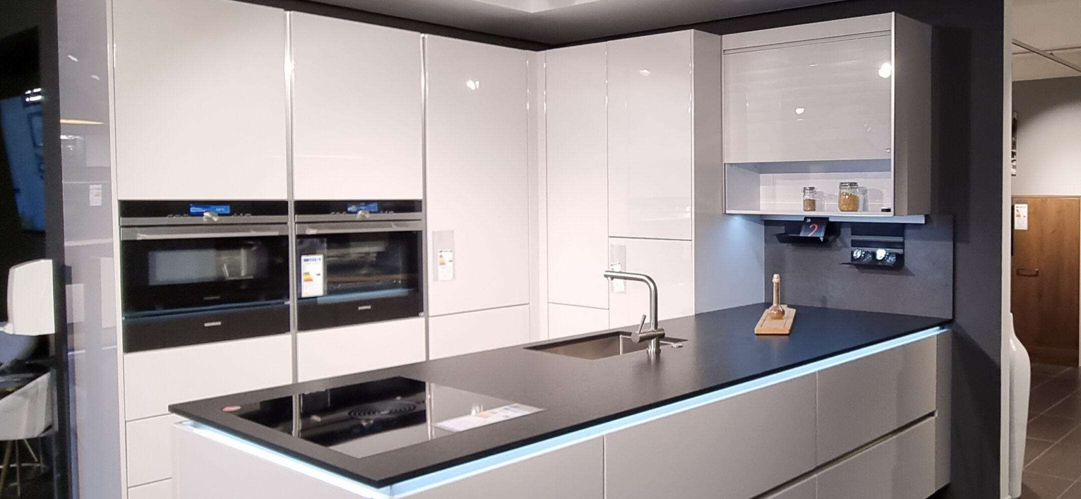 Hochwertige grifflose Inselküche mit schwarzer Naturstein-Arbeitsplatte