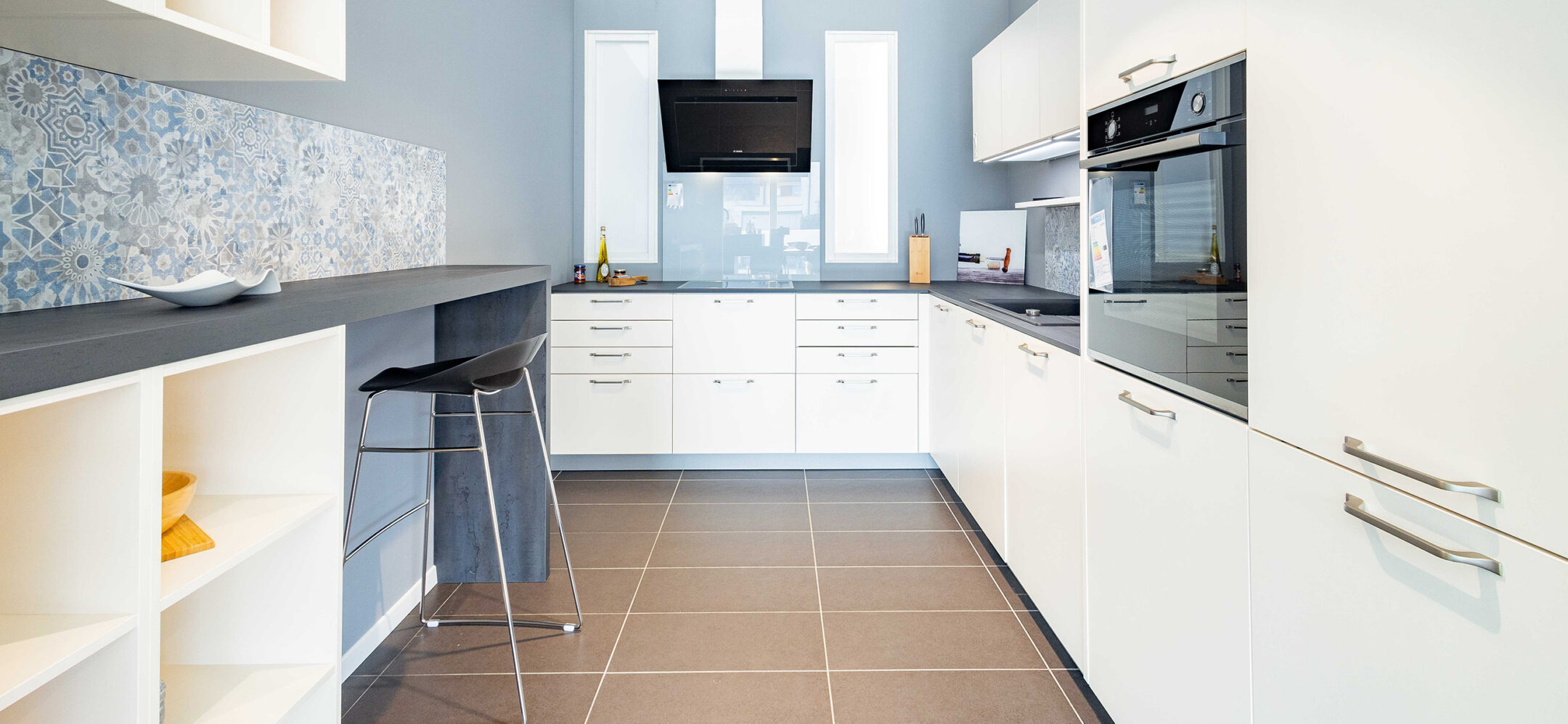 Klassische helle Küche mit grauer Arbeitsplatte und Sitzgelegenheit