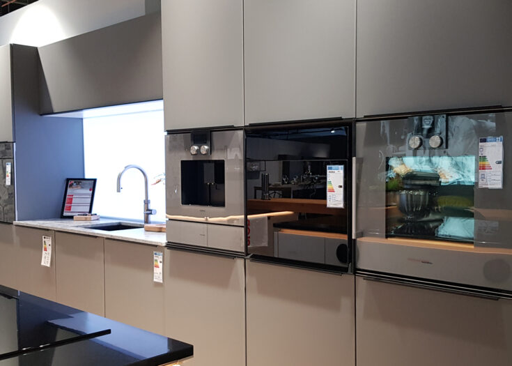 Einzeilige Küche mit grauen Glas-Fronten und Elementstein-Arbeitsplatte