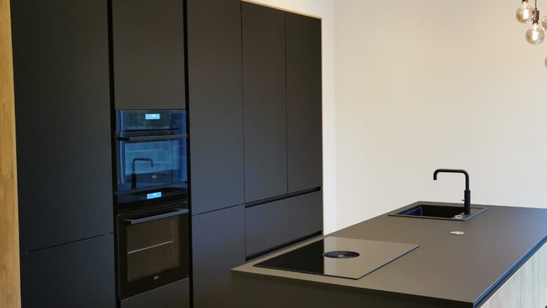 PLANA Küchenstudio Lippstadt Kundenküche mit schwarzen grifflosen Fronten, hochwertigen Einbaugeräten und dunkler Arbeitsplatte