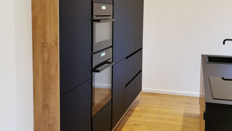 PLANA Küchenstudio Lippstadt Kundenküche mit schwarzen grifflosen Fronten, hochwertigen Einbaugeräten und dunkler Arbeitsplatte