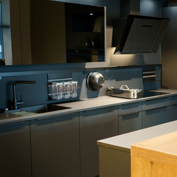 Zweieilige Küche mit grauen Fronten und schwarzen Griffleisten