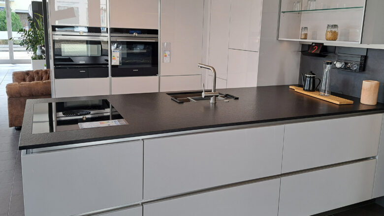 Hochwertige grifflose Inselküche mit schwarzer Naturstein-Arbeitsplatte