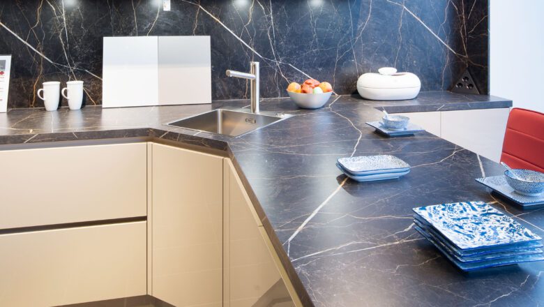 PLANA Küchenausstellung Hilden L-Küche mit Arbeitsplatte und Nischenrückwand in Marmor-Optik