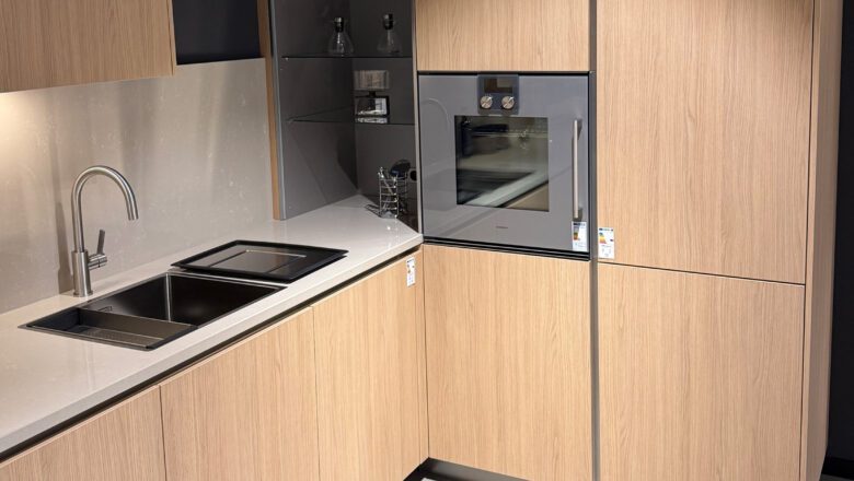 L-Küche mit heller Elementstein-Arbeitsplatte und Gaggenau-Backofen